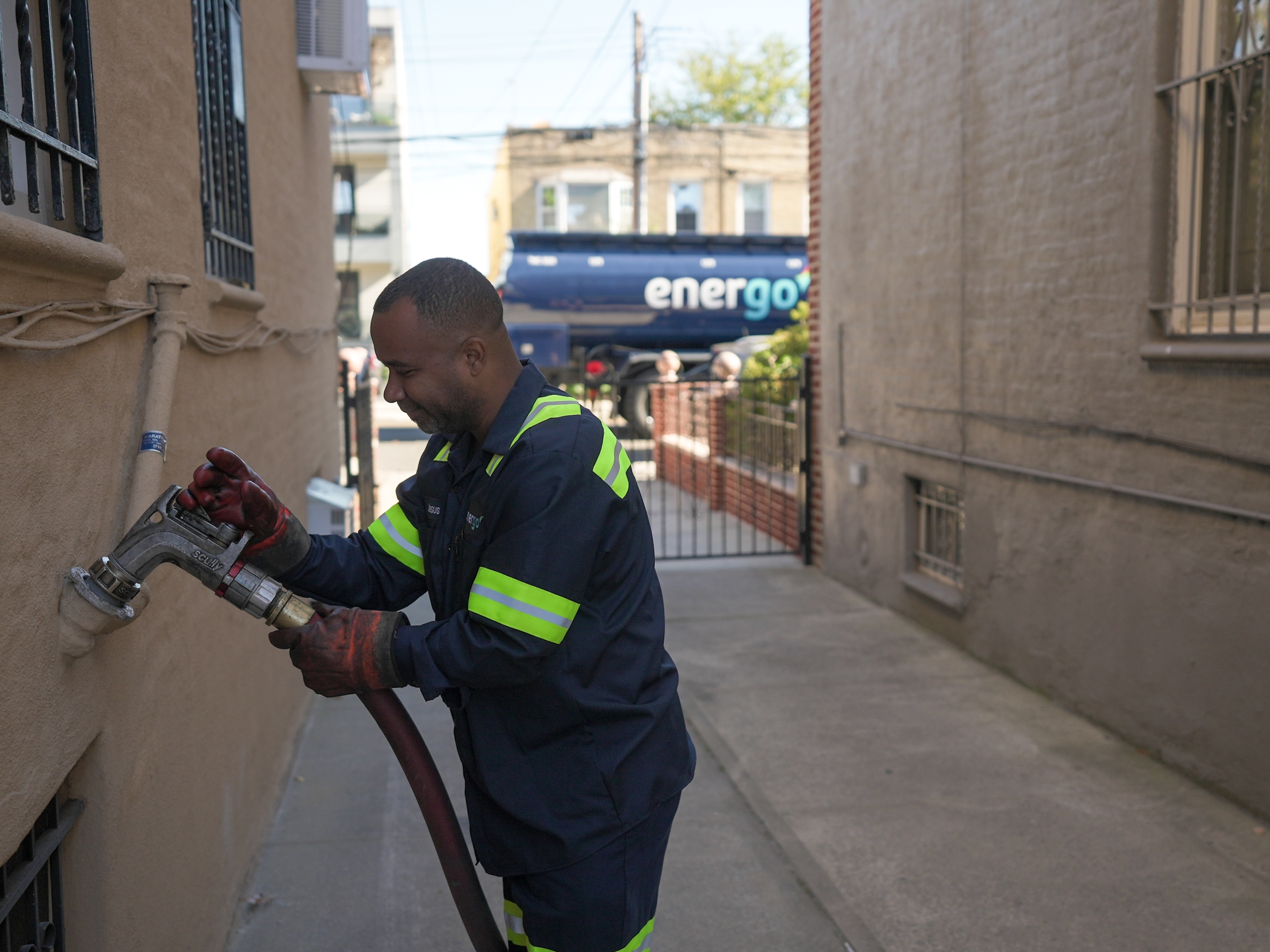 Energo employee with a hose in an alley with an Energo truck in the background
