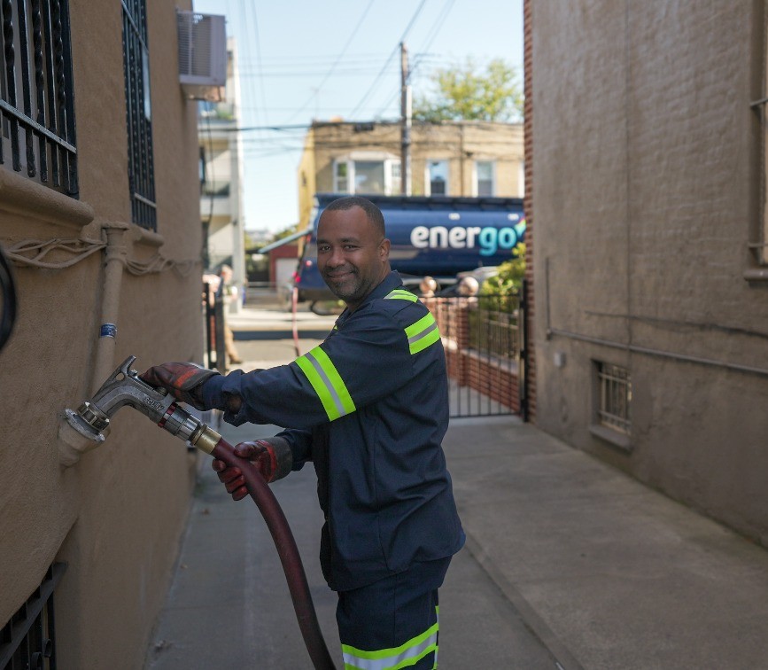 Energo employee with a hose in an alley with an Energo truck in the background