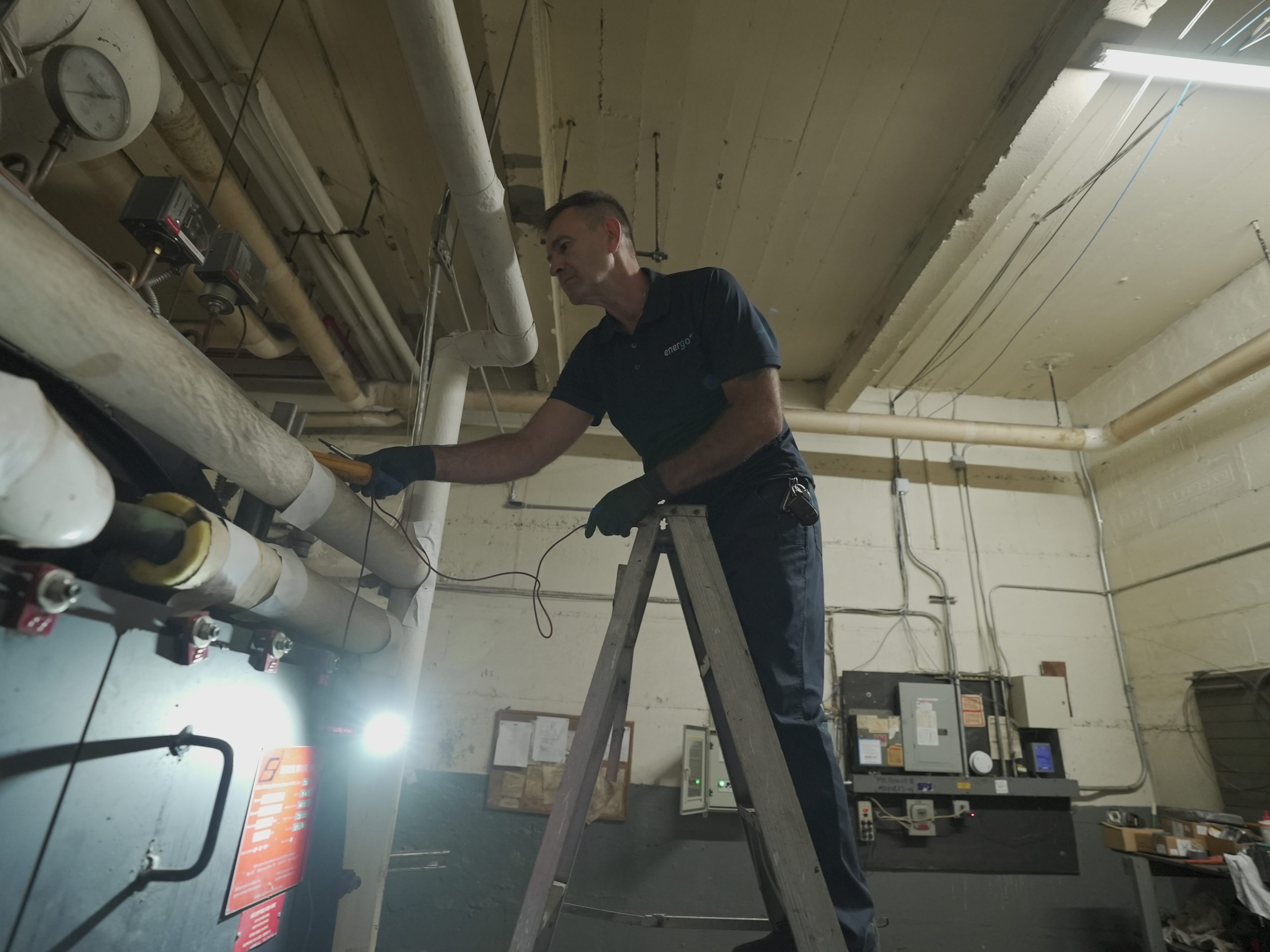 Energo technician standing on ladder inspecting for Local Law 62