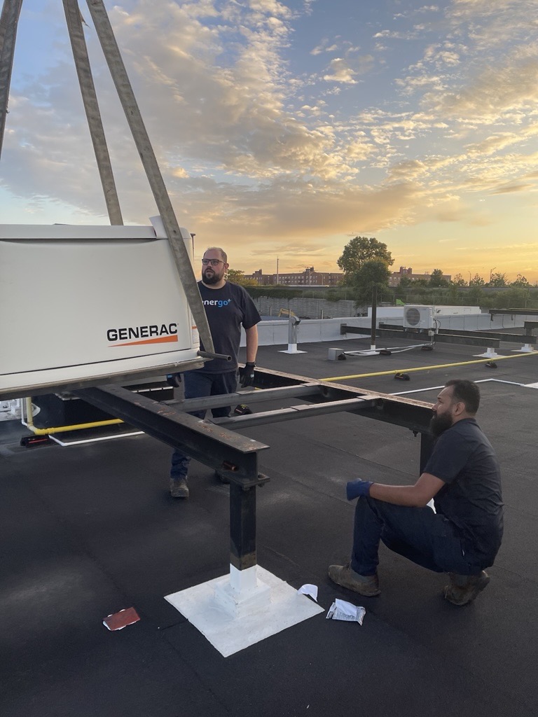 Energo technicians installing Generac generator on rooftop at sunset