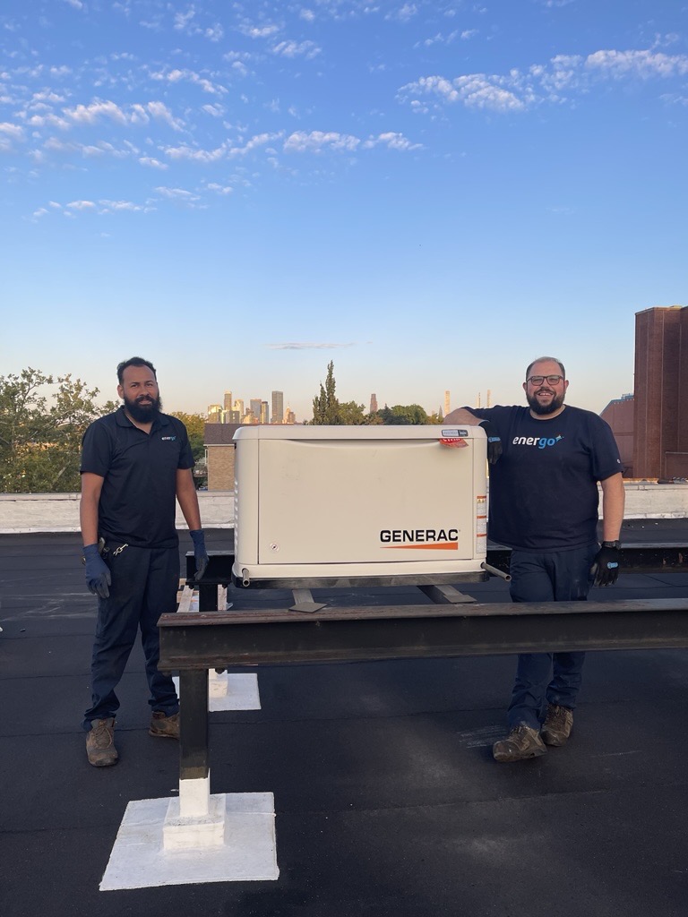 Two Energo technicians standing with installed Generac generator