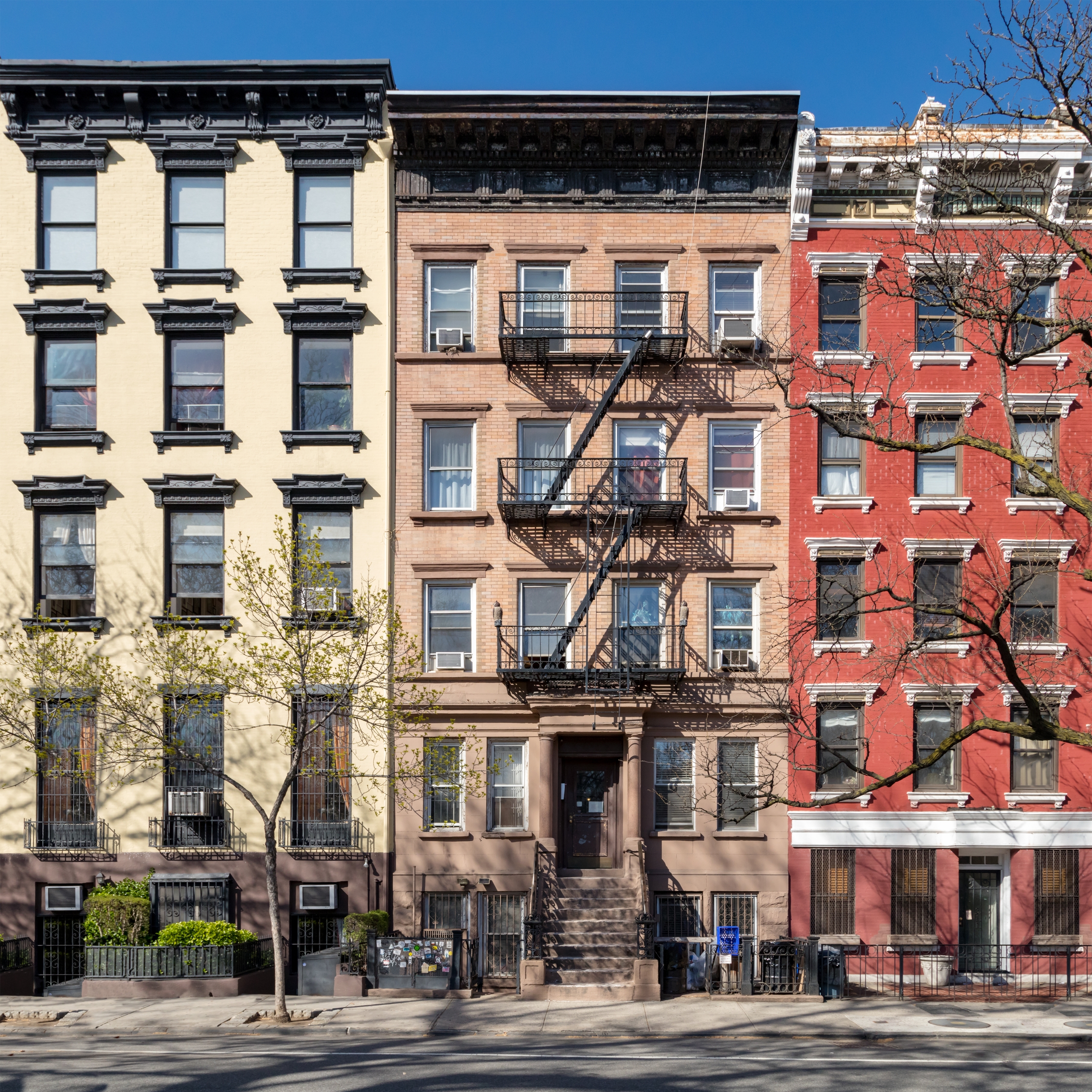 Row of NYC brownstone apartment buildings in sunlight