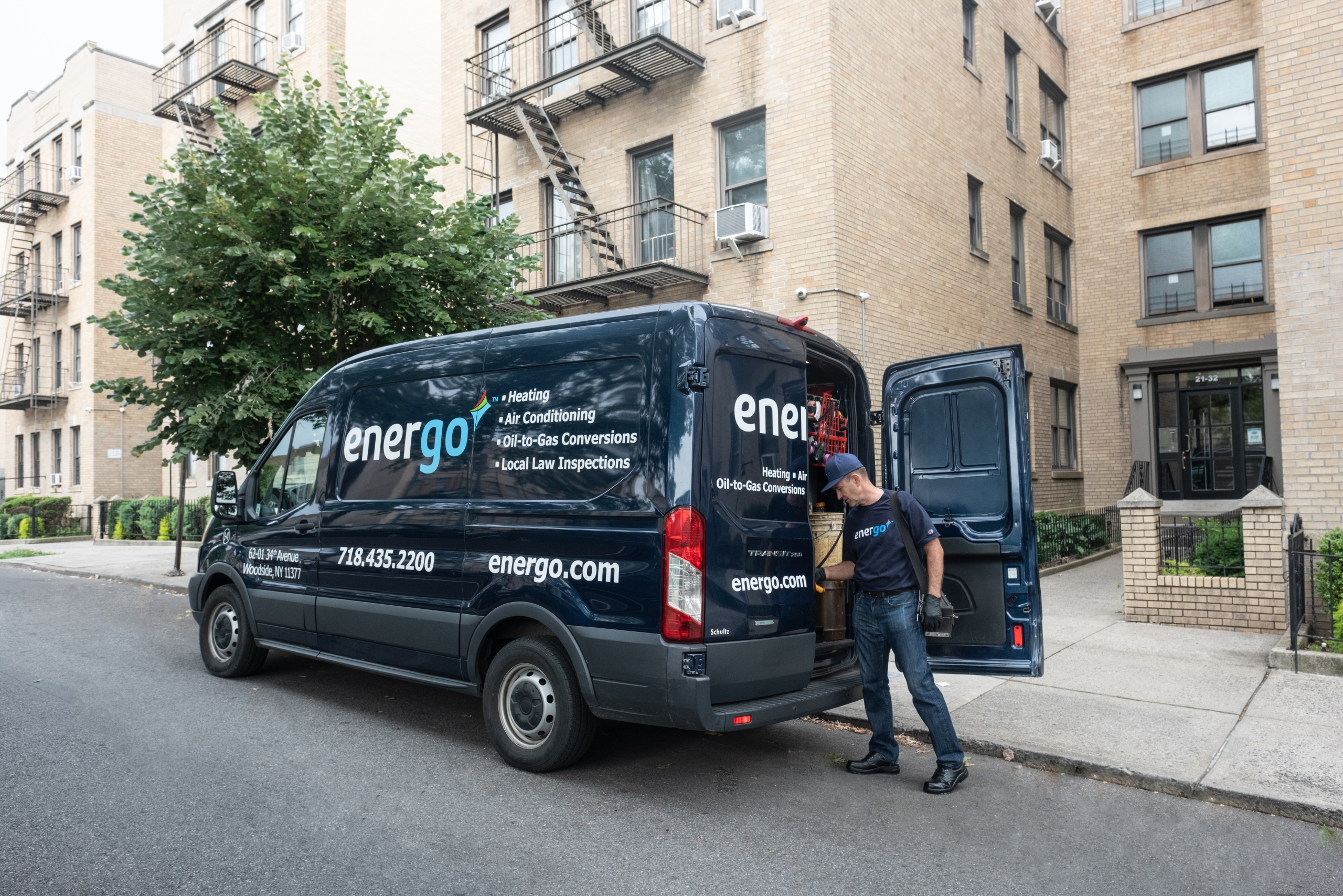 Energo technician unloading tools from branded service van parked curbside